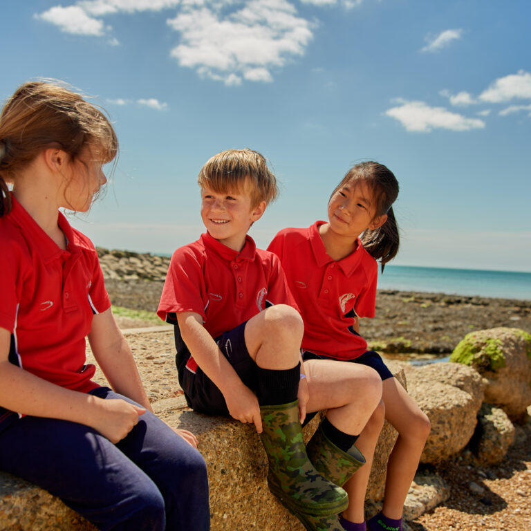 Three students sat on rocks at the beach