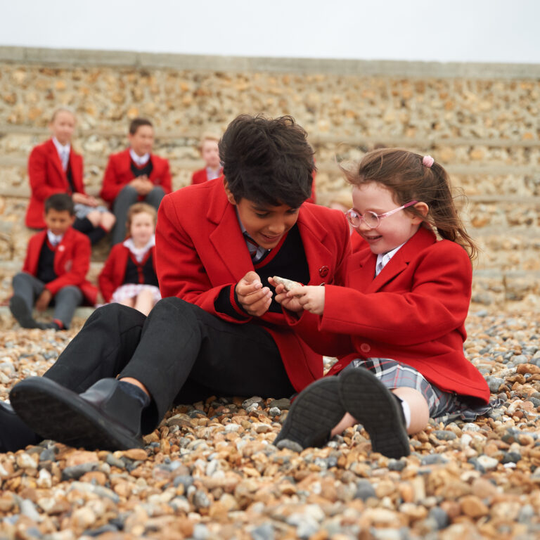 students sat on a pebble beach