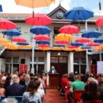 Umbrellas above adults sat in benches