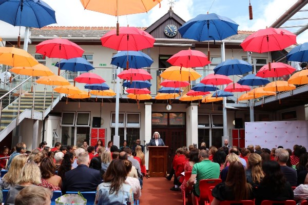Umbrellas above adults sat in benches
